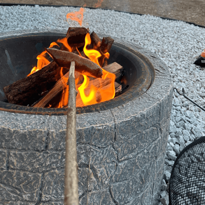 laužavietė su betono imitacija lauke. Kepama dešrelė ant medinės lazdos.